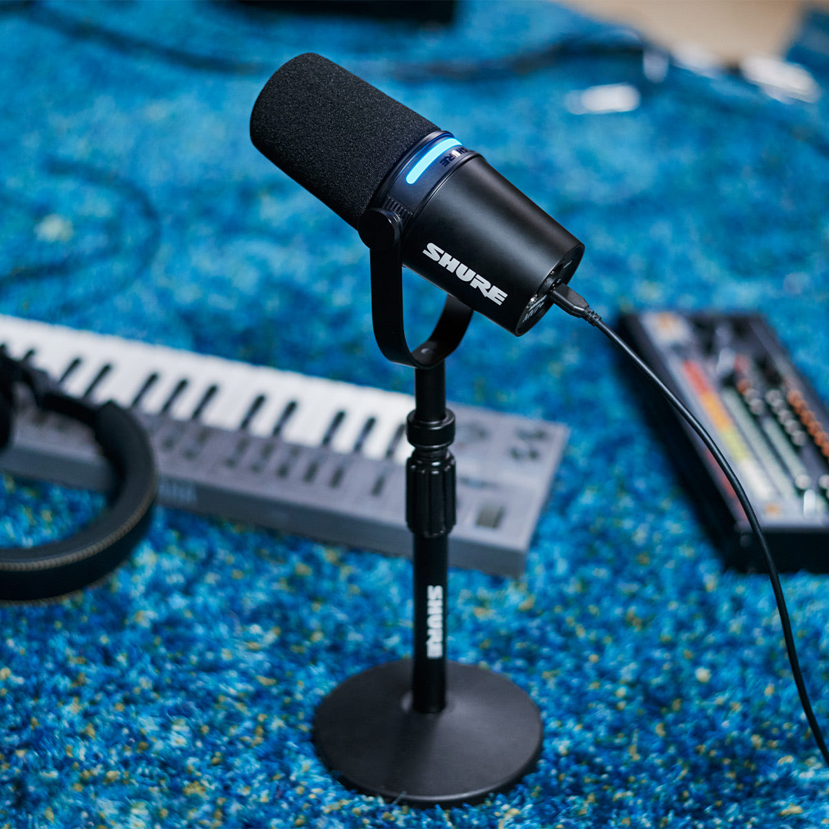 Shure MV7+ black microphone on a desktop stand in a home music studio